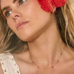 Model in Bixby jewellery. Gold necklace with red hearts 